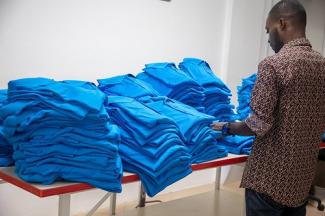 Man inspecting table full of blue shirts