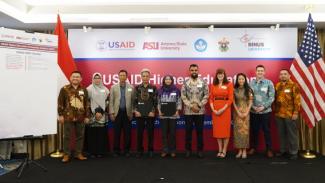 Ten representatives from USAID Indonesia and from Indonesian and U.S. universities are standing between the Indonesian and U.S. flags.
