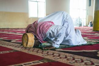 A man kneeling in prayer in the Islamic tradition.