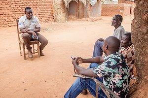 Man sitting across three other men in a village