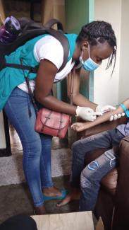 A health care worker collects a blood sample from a child living with HIV to test their viral load (how much of the HIV virus is in their body).