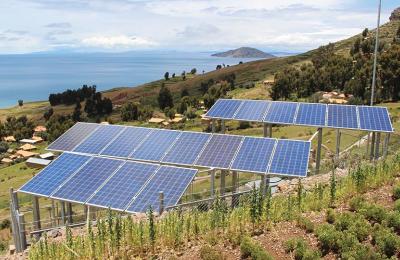 Photo of solar panels on a sunny green hillside shore