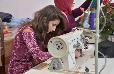 A young aspiring fashion designer learns the art of sewing at a USAID-supported tailoring business in Masalli.