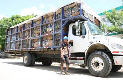 Alfonso Frías stands in front of his full waste collection truck in the Dominican Republic.