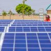 A female Nigerian solar technician inspects a photovoltaic array in a rural community
