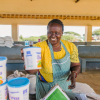 A smiling woman in Kenya stacks tubs labeled Diria.
