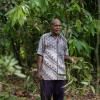 Indonesian vanilla farmer Augustinas Daka stands with the vanilla plants