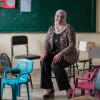 Smiling woman sits in a classroom surrounded by small chairs