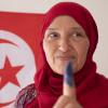 A Tunisian woman holds up an ink-dyed finger to signify she has cast a vote