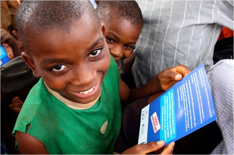 Two young boys read through a community change bulletin from USAID in Tanzania.