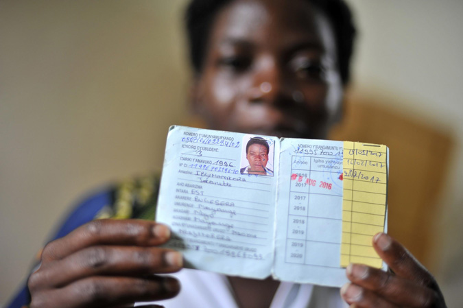 A woman holds up her health insurance card.