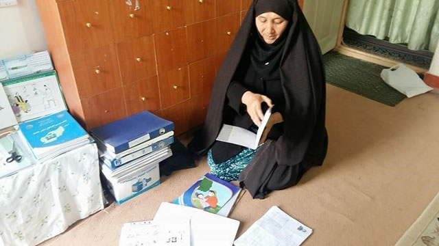 Photo of Fatima Kahdem sitting, reading health books. Photo credit: Nazir Ahmad Rahmani/Challenge TB