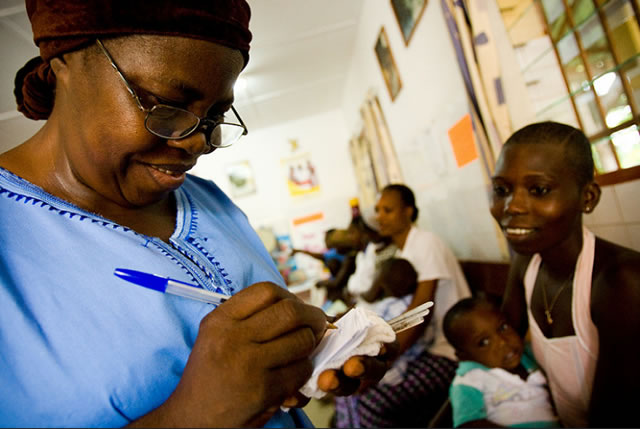 Photo of a female doctor in Malawi writing a prescription for a patient. Photo credit: USAID